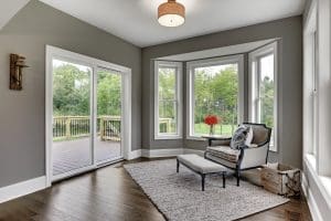 The living room of a home with white sliding patio doors and a bay window