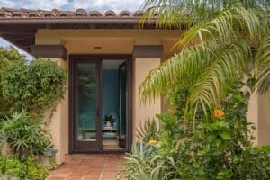 Luxurious tropical garden outside of home with tall hinged patio doors leading inside